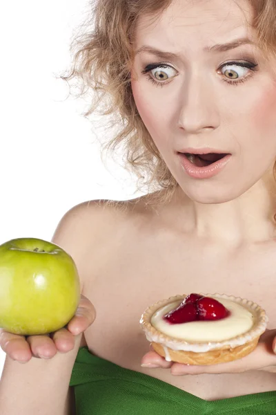 Young cheerful woman, choosing between apple and cake — Stock Photo, Image