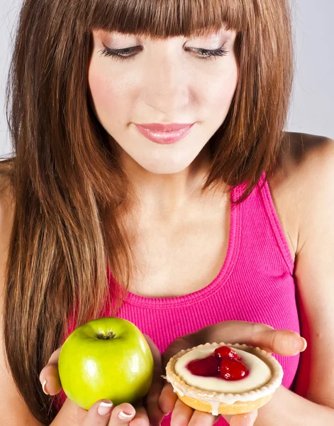 Woman with apple and cake in hands — Stock Photo, Image