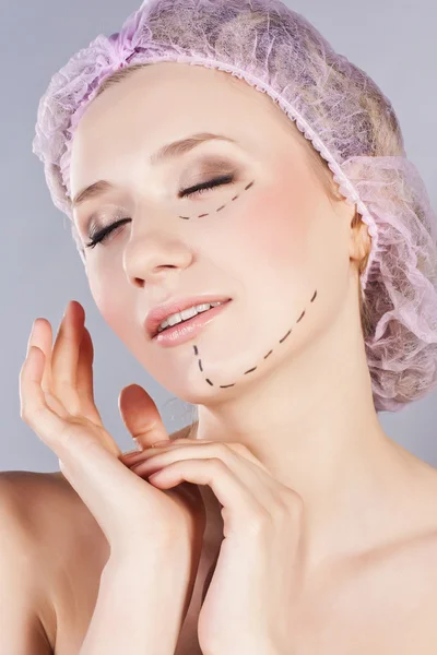 Vacker ung kvinna, med perforering linjer på hennes ansikte innan plastikkirurgi operation — Stockfoto