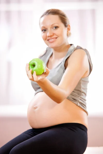 Νέα έγκυος γυναίκα που κρατά το πράσινο μήλο — Φωτογραφία Αρχείου