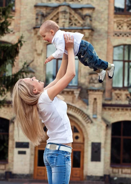 Szczęśliwa młoda kobieta, podnoszenie jej syn wysoko — Zdjęcie stockowe
