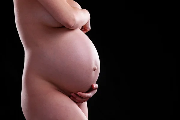 Young naked pregnant woman over black — Stock Photo, Image