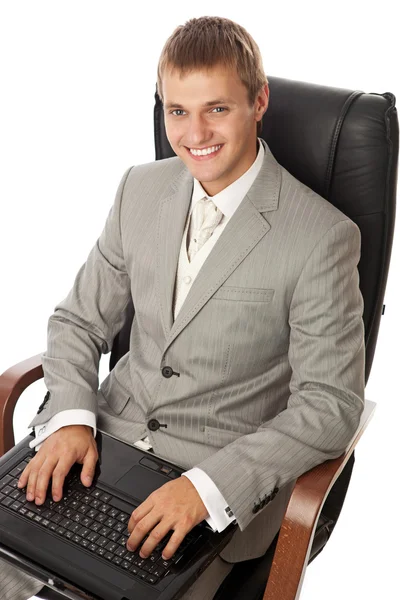 Красивый молодой человек с ноутбуком, сидящий в кресле — стоковое фото