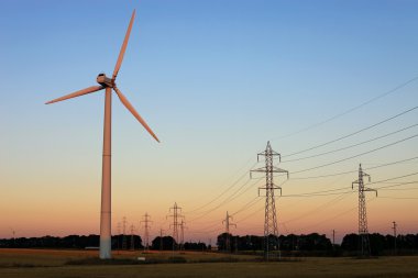 elektriciteit pylonen en windturbines tegen hemel bij zonsondergang