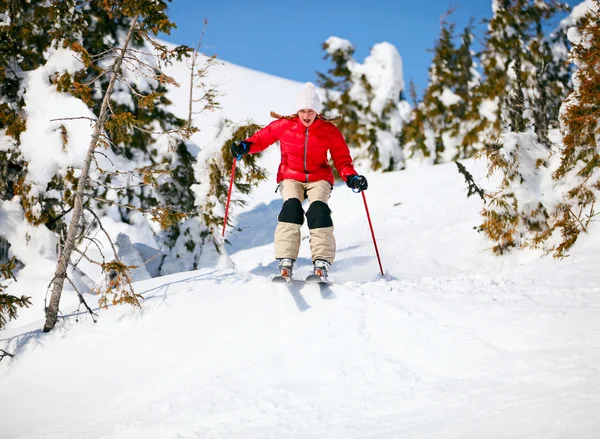 Unga kvinnliga skidåkare hoppning i snöig backe — Stockfoto