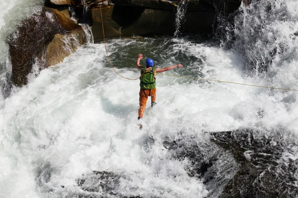 Young man rope jumping in rapid waters of a mountainous river