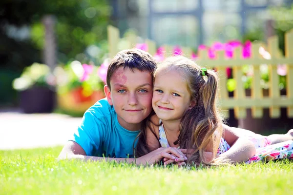 Cute brother and sister lying on the grass outdoors — Stock Photo, Image