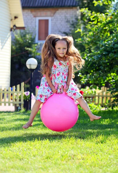 Schattig vierjarig meisje bouncen op een grote bal buiten — Stockfoto