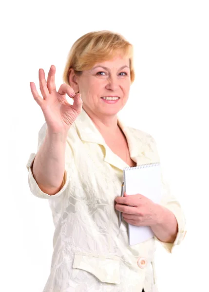 Веселая зрелая деловая женщина с ручкой и блокнотом давая знак ОК, изолированные над белым — стоковое фото
