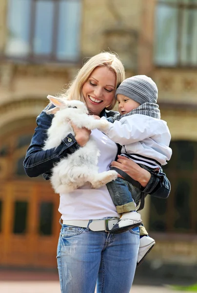 Young woman showing a fancy rabbit to her son outdoors — Stock Photo, Image