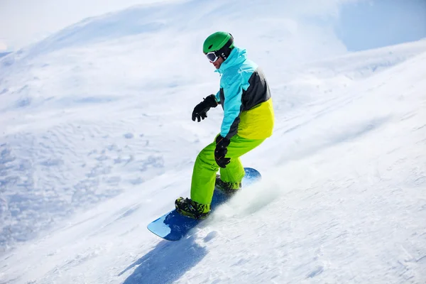 Snowboarder scivolare giù per un pendio in una giornata di sole — Foto Stock
