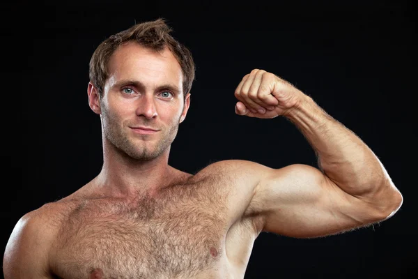 Primer retrato del hombre musculoso flexionando su bíceps contra el negro — Foto de Stock