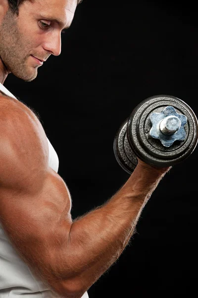 Muskulöser Mann hebt Hantel auf schwarzem Hintergrund — Stockfoto