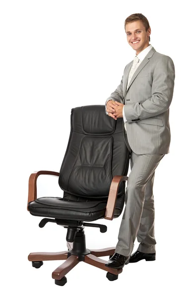 Handsome young man standing next to an armchair — Stock Photo, Image