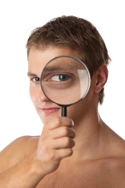 Cute young man looking through a magnifying glass — Stock Photo, Image