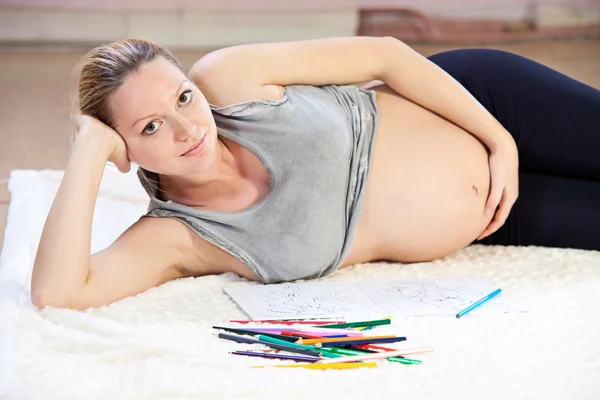 Jolie jeune femme enceinte dessiner avec des crayons — Photo