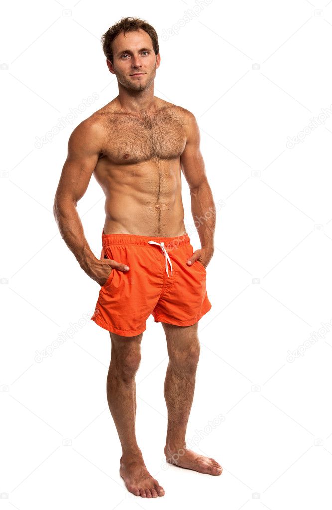 Muscular young man in swimwear standing on white