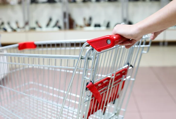 Woman pushing shopping cart in shoe store, close-up — Stock Photo, Image