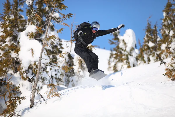 Snowboarder pulando na encosta da montanha — Fotografia de Stock