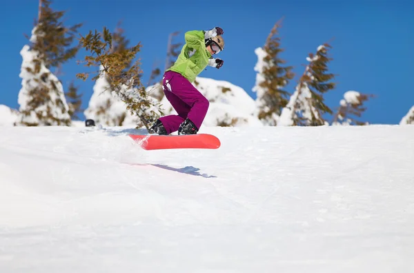Mulher snowboarder pulando na encosta da montanha — Fotografia de Stock