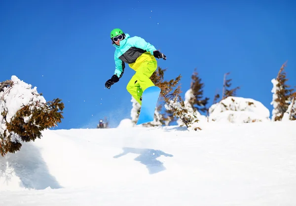 Snowboarder pulando na encosta da montanha — Fotografia de Stock