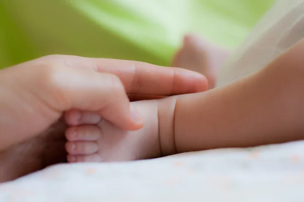 Mom's arm with child's foot — Stock Photo, Image