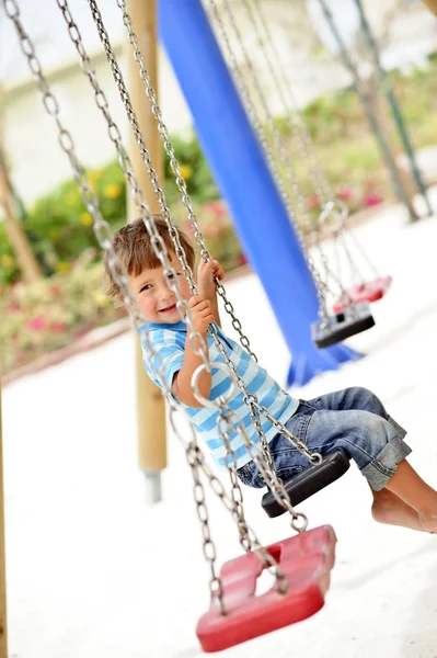 Little boy swinging on chain swing — Stock Photo, Image