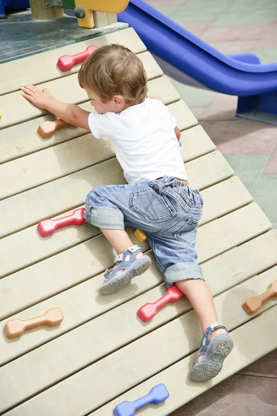 Liten pojke klättra på lekplats. — Stockfoto