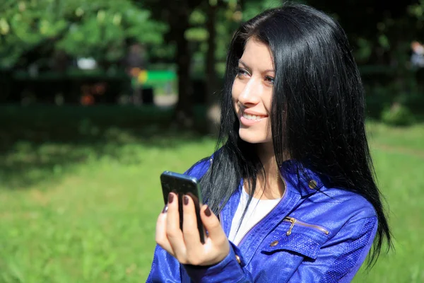 Jovem mulher olhando para o telefone e sorrindo — Fotografia de Stock