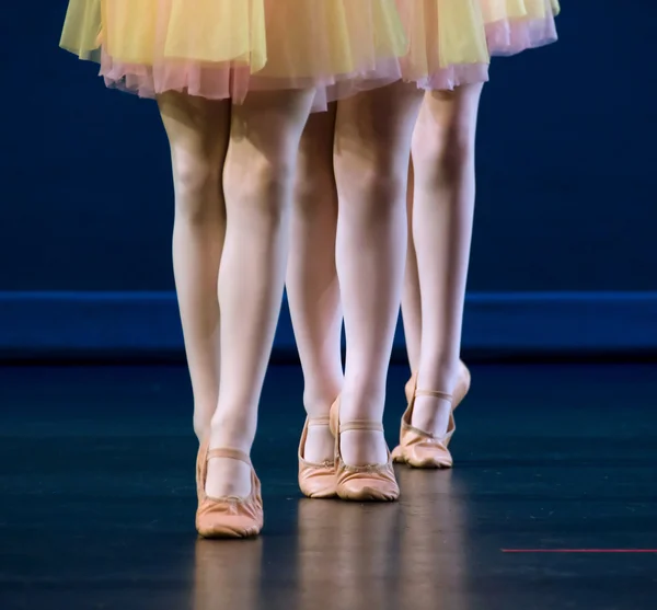 เท้าของนักเต้นสามคนในรองเท้าแบนและกระโปรงสีเหลืองและสีชมพู — ภาพถ่ายสต็อก