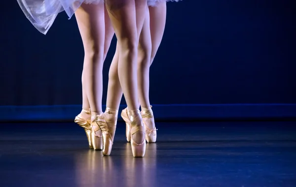 Feet of trio of ballerinas on pointe dark blue floor — Stock Photo, Image
