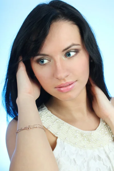 Привлекательная женщина, исправляя ее волосы на синем фоне — стоковое фото