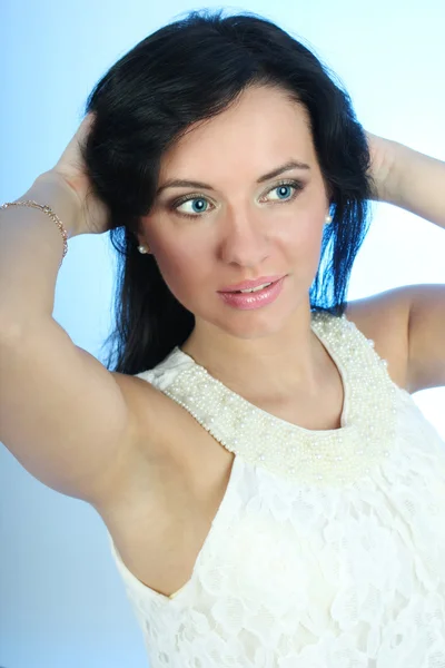 Attraktive Frau, die ihr Haar auf blauem Hintergrund zu korrigieren — Stockfoto