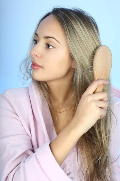 Young woman in bathrobe with comb — Stock Photo, Image