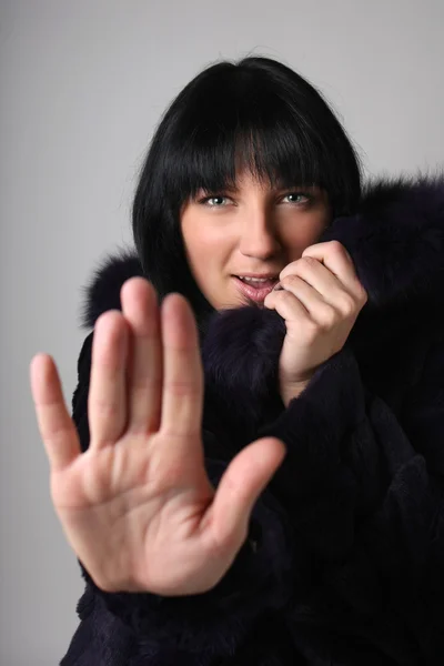 Jovem mulher com casaco de pele, fazendo o gesto de parada — Fotografia de Stock
