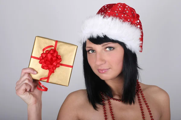 Beautiful brunette woman in santa hat holding golden present — Stock Photo, Image