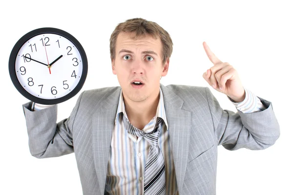 Förvånad affärsman i grå kostym innehar en klocka — Stockfoto