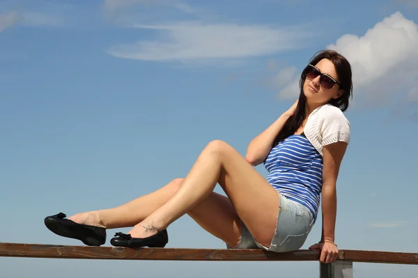 Üzerinde mavi gökyüzü oturan genç kadın — Stok fotoğraf