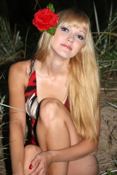 Blond kobieta z kwiatem we włosach siedzi — Zdjęcie stockowe