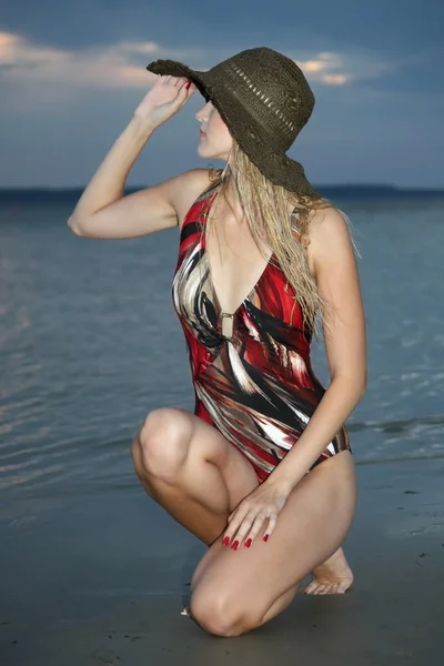 Blond kobieta siedzi na plaży — Zdjęcie stockowe