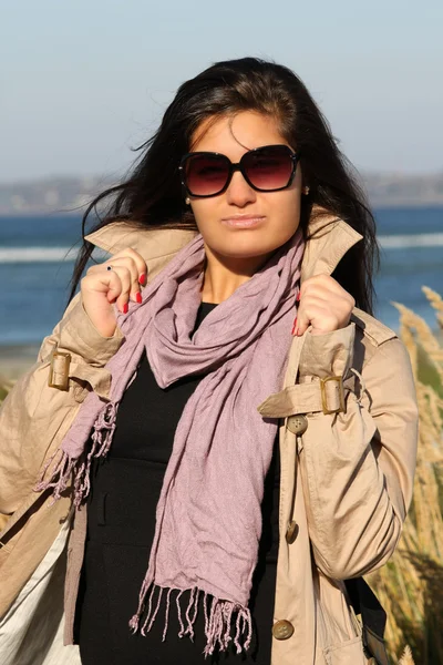 Woman in beige autumn coat standing at beach — Stock Photo, Image