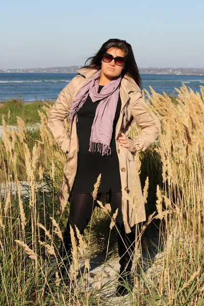Žena v béžové podzimní kabát stojí u moře — Stock fotografie