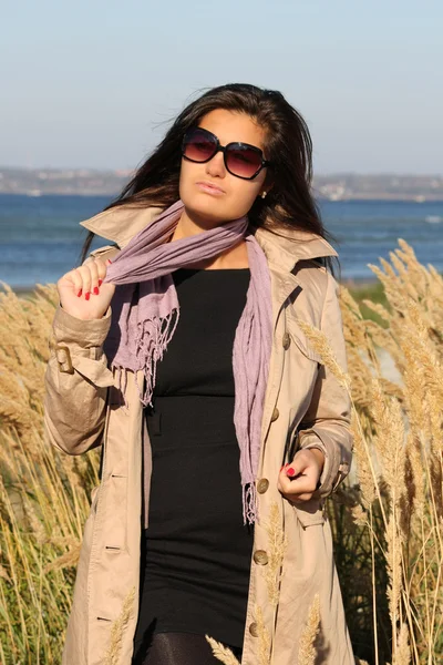 Femme en manteau automne beige, posant à la plage — Photo