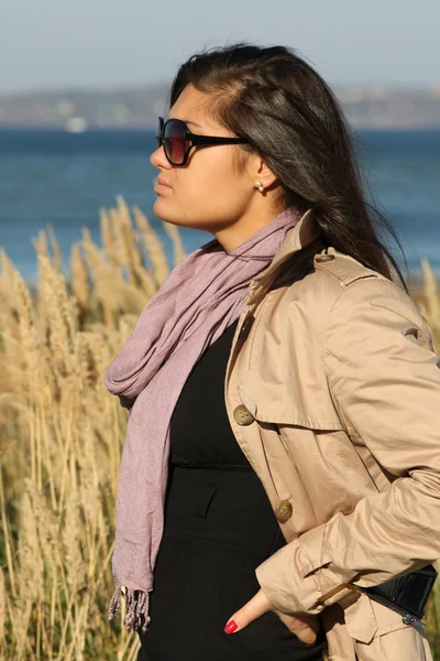 Kvinna i beige höst kappa stående vid havet — Stockfoto
