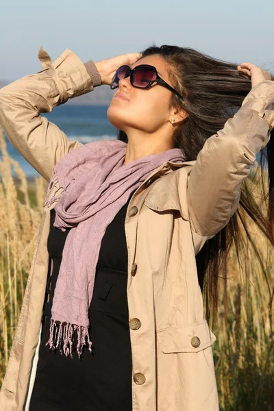 Дівчина в бежевому осінньому пальто, що виправляє волосся — стокове фото