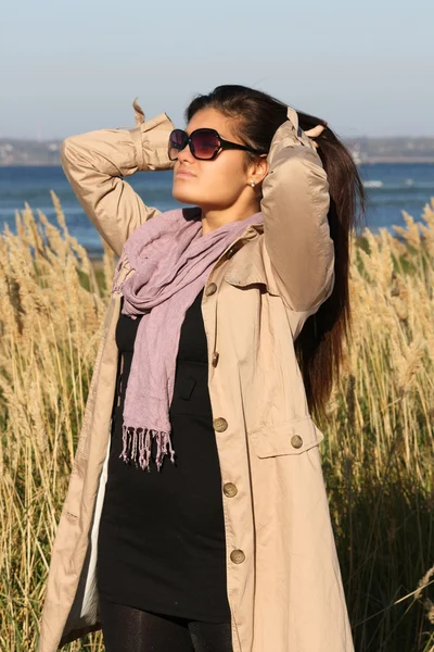 Attractive girl in beige autumn coat correcting her hair — Foto Stock