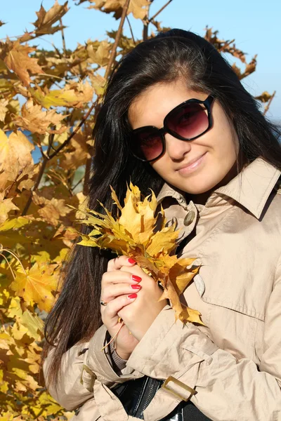 Mulher bonita em bege casaco Outono com folhagem dourada — Fotografia de Stock