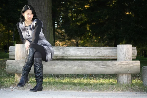 Atraktivní žena pózuje na lavičce v parku — Stock fotografie