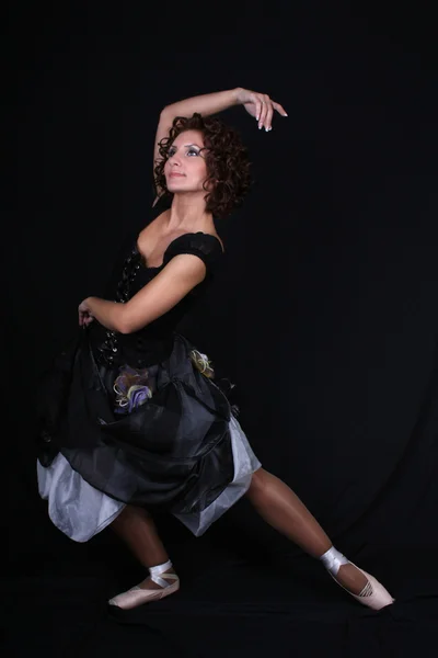 Балерина в чорне плаття постановки на темному тлі — стокове фото