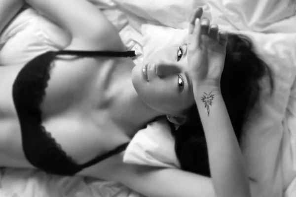 Sexy schöne Frau auf Bett schwarz / weiß liegend — Stockfoto